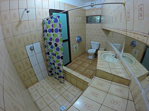 Bathroom with a walk-in shower behind a spotted curtain, toilet and sink, blue and white tiles.