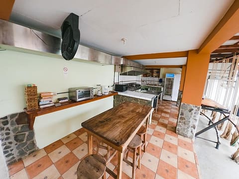 Kitchen counter with a toaster oven and a wooden table with stools, terracotta checkerboard floor.