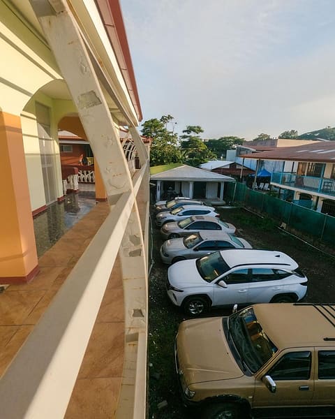 Cars in the hostel's parking area, seen from the upstairs walkway.