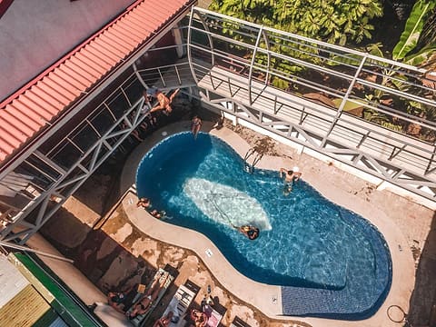 The kidney-shaped pool seen from above, with loungers along the deck and the upstairs walkway railing.