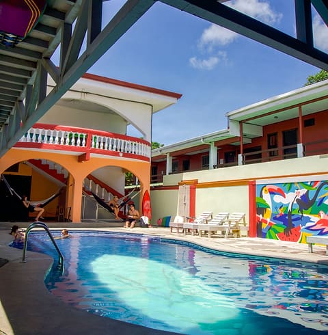 The pool in front of the orange-arched building and the colourful toucan mural.