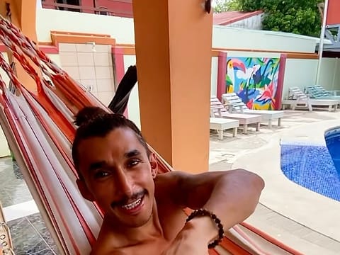 Hammock, orange arches, toucan mural, loungers and the blue-tiled pool at Hostel de Haan.