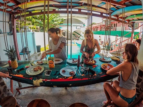 Guests sharing plates of food around a round painted table under a colourful ceiling.