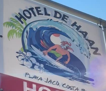 Close-up of the painted wave on the hostel sign, curling around a cartoon surfer and an orange sun.