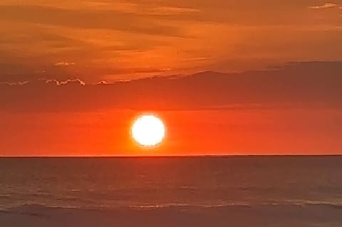 Orange sunset over the Pacific at Jacó, the sun just above the horizon.