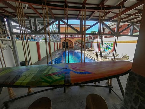A painted surfboard turned into a table, rope swings hanging from the beams and the pool behind.
