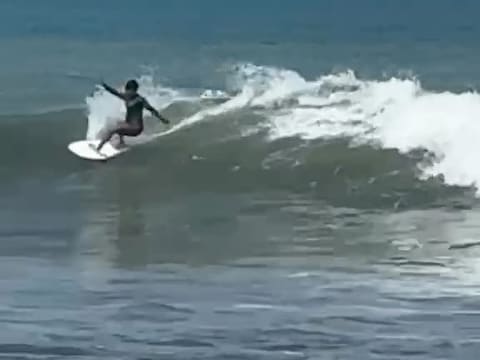 A surfer riding a small wave at Jacó, whitewater peeling to the right.